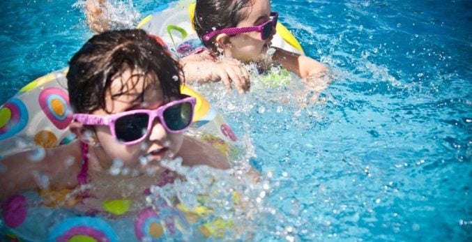 children-wearing-pink-sunglassess-swimming-splashing-on-lilo-rings-wearing-glasses